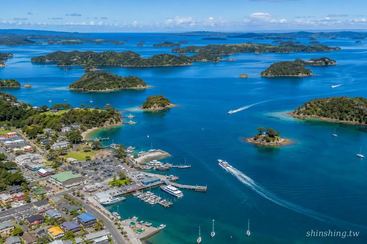 Paihia 碼頭空拍，島嶼灣 Bay of Islands 144 座翠綠小島在晨光中一字排開，遊艇靜靜停泊於湛藍海灣