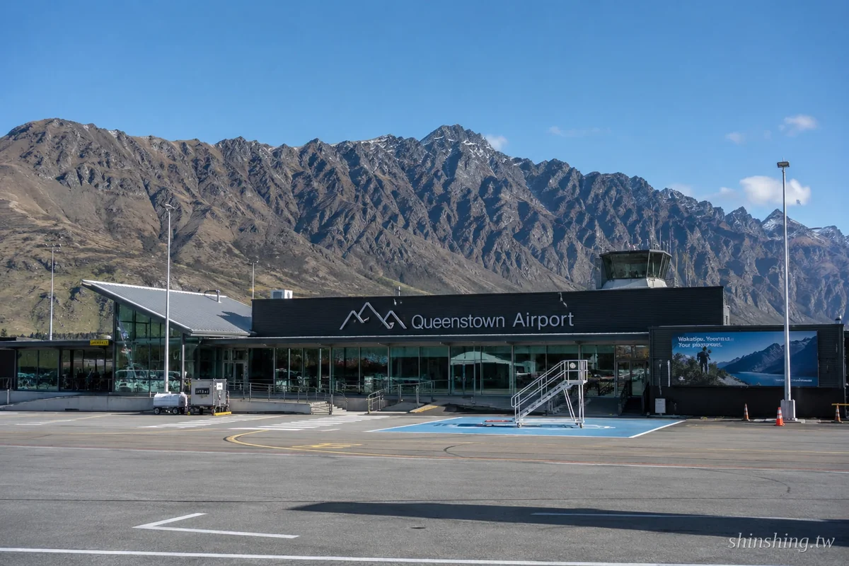 皇后鎮機場 ZQN 航廈外觀，背景是南阿爾卑斯山雪山與瓦卡蒂普湖，湛藍天空