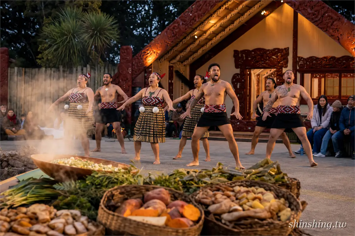羅托魯瓦毛利文化晚宴的 Hāngi:藤籃裡剛出土的地瓜、南瓜與玉米冒著蒸氣,後方表演者在雕刻會堂前跳 haka