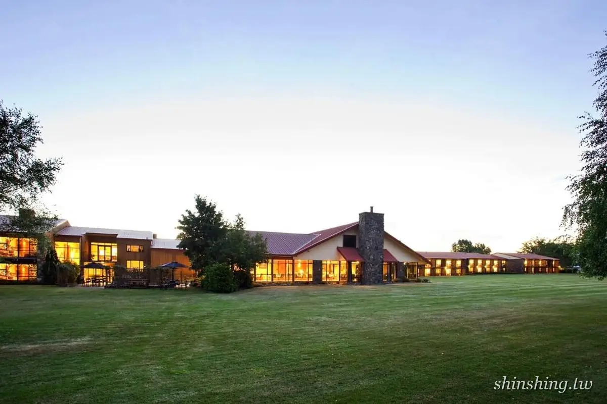 Distinction Mackenzie Country Hotel 的長條形建築在黃昏亮起暖黃燈光,前方是一大片修剪整齊的草坪