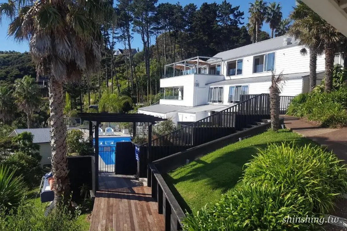 Waiheke Island Resort 白色主樓、泳池與棕櫚樹庭園